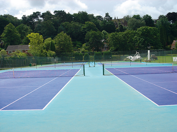 Court de tennis bleu avec trois terrains dans un environnement vert