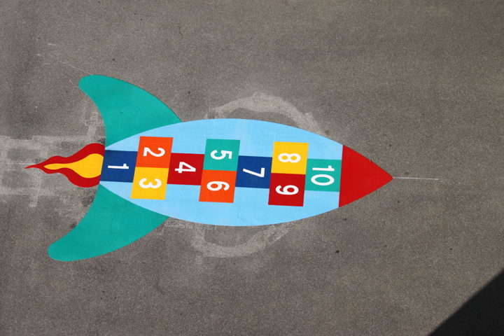 Fusée multicolore comme jeu de saut sur l'asphalte, avec des cases numérotées de 1 à 10.