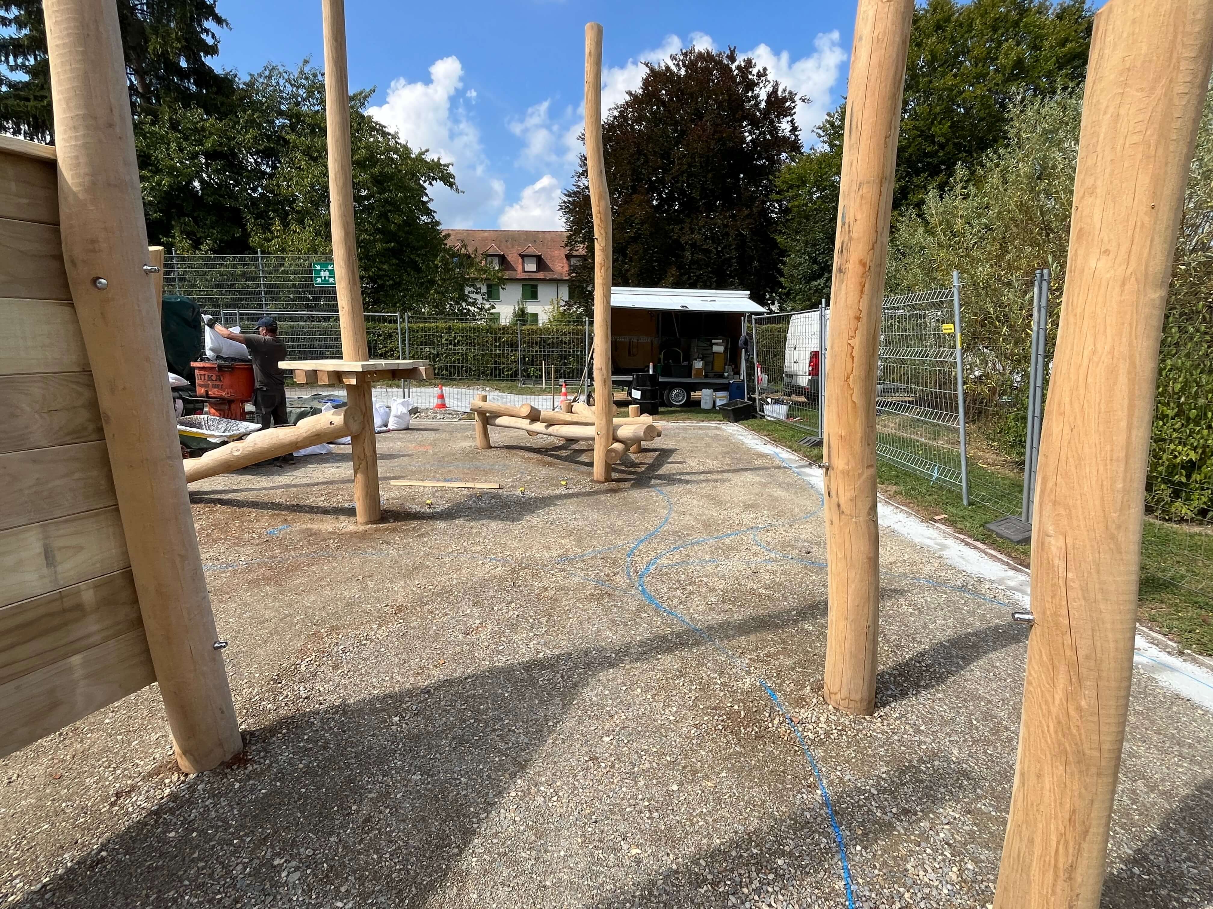 Baustelle eines Spielplatzes mit Holzstrukturen in einem Park bei sonnigem Wetter