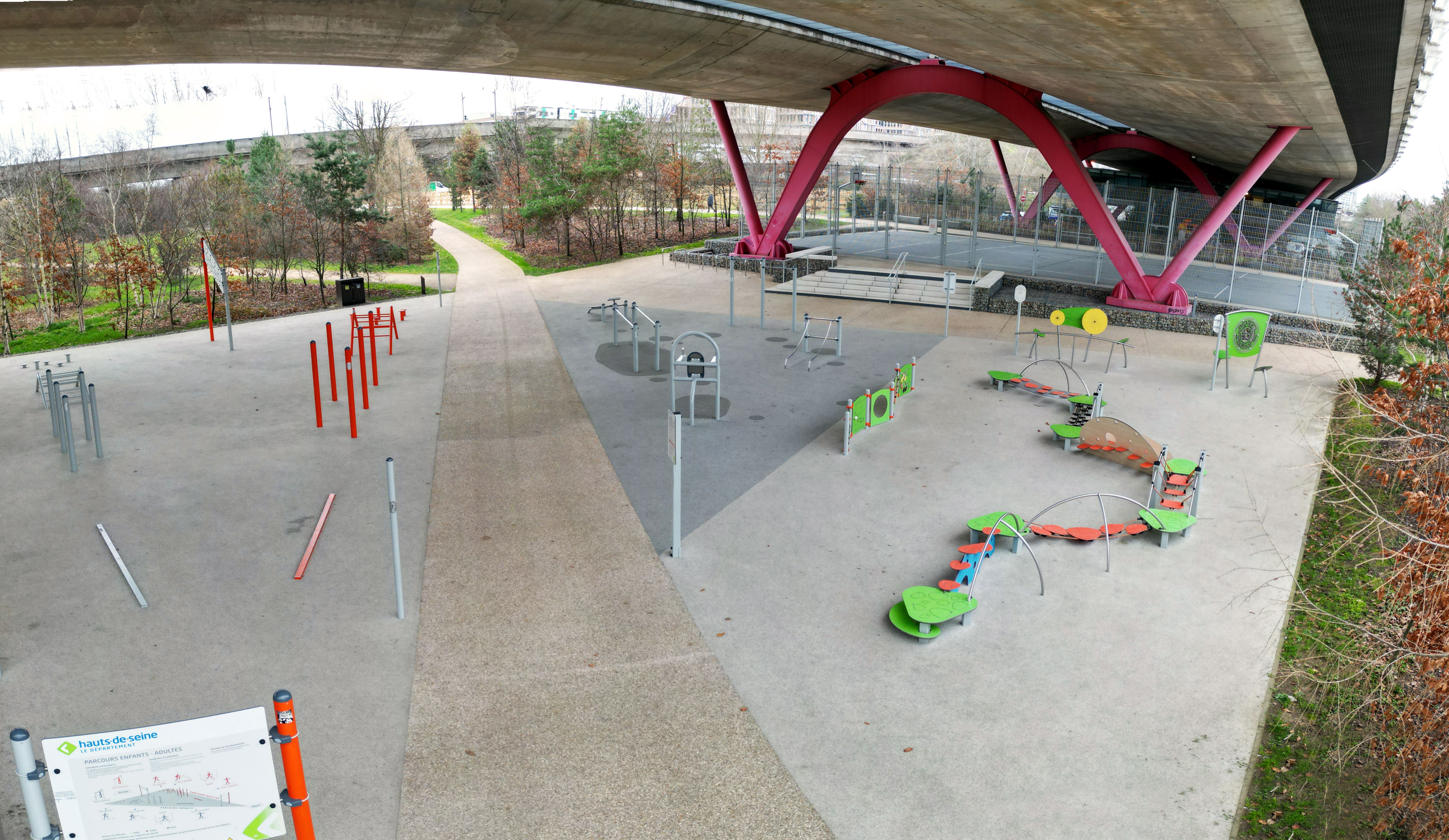 Zone d'activité sous un pont avec différents appareils de fitness et de jeu