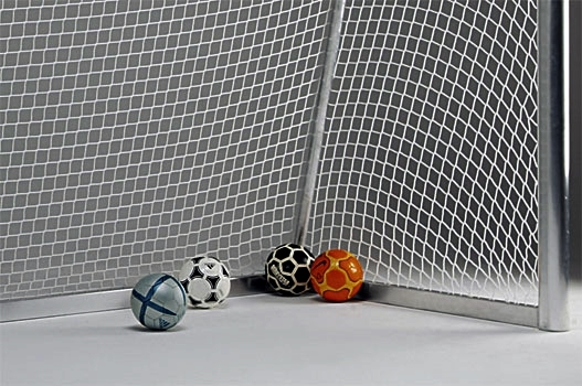 Quatre ballons de foot différents placés dans un coin du but