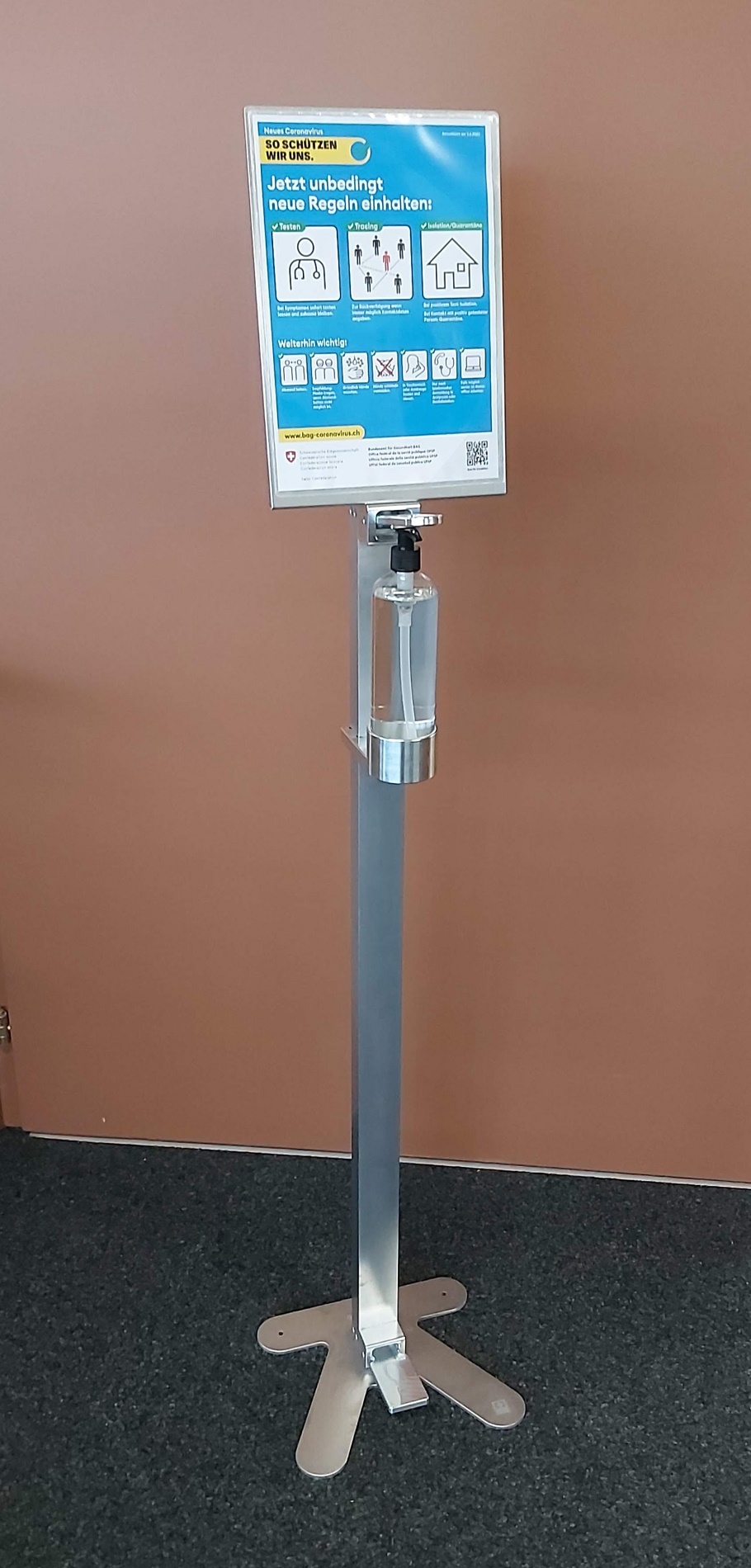 Un distributeur de désinfectant avec un panneau d'information sur le respect des nouvelles règles d'hygiène et de comportement.