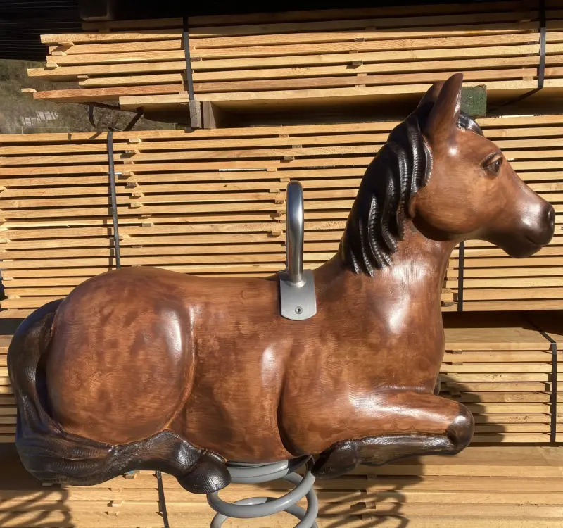 Ein robustes Holz-Pferd-Schaukelspielzeug, ideal für den Spielplatz im Garten, vor einem Stapel Bretter
