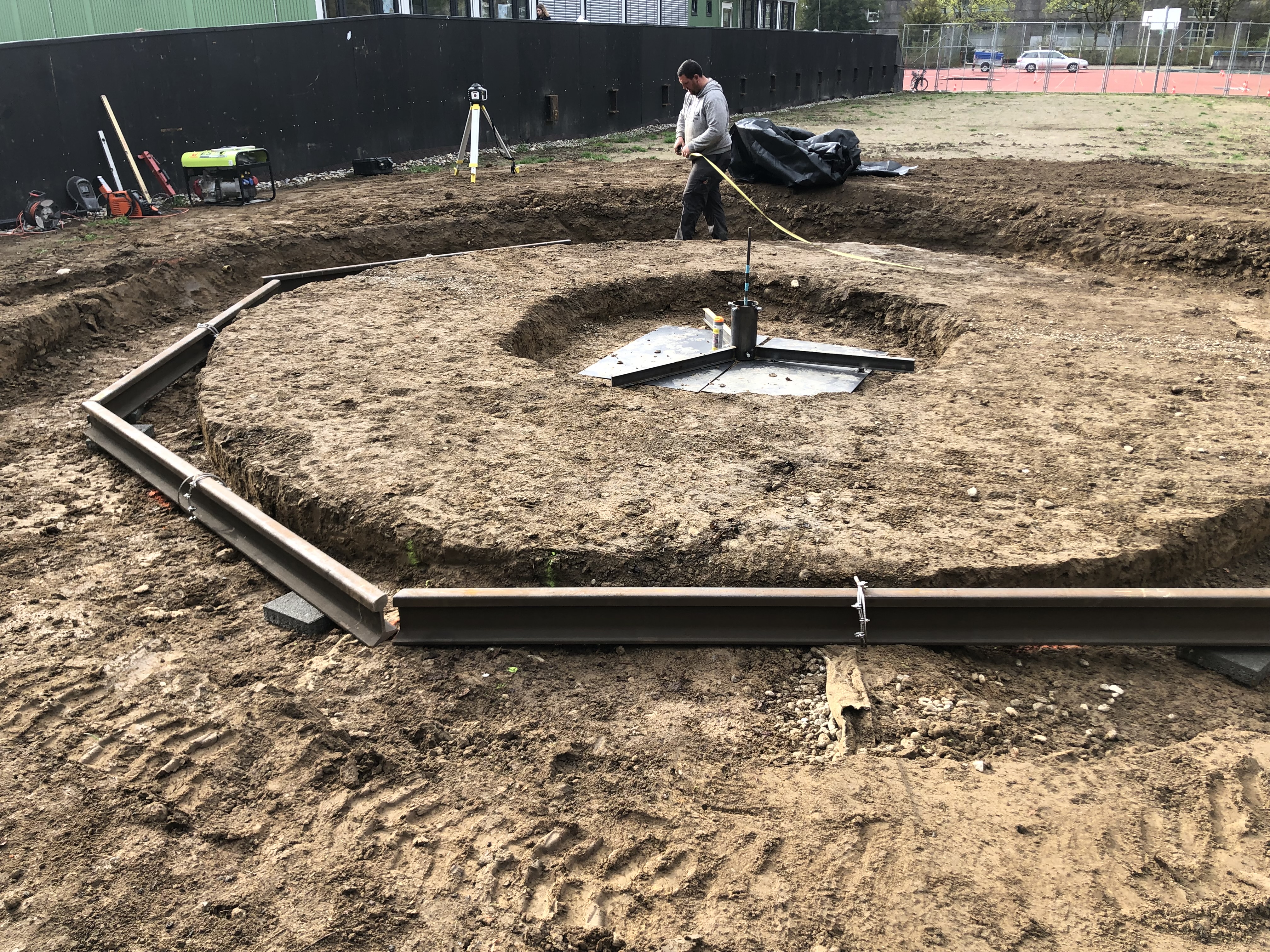 Ein Arbeiter bei der Konstruktion einer runden Fundamentstruktur mit Stahlverstärkung auf einer Baustelle im Freien