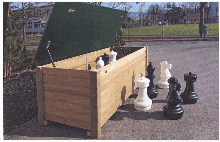 Geöffnete Holztruhe mit Schachfiguren auf einem Asphaltplatz