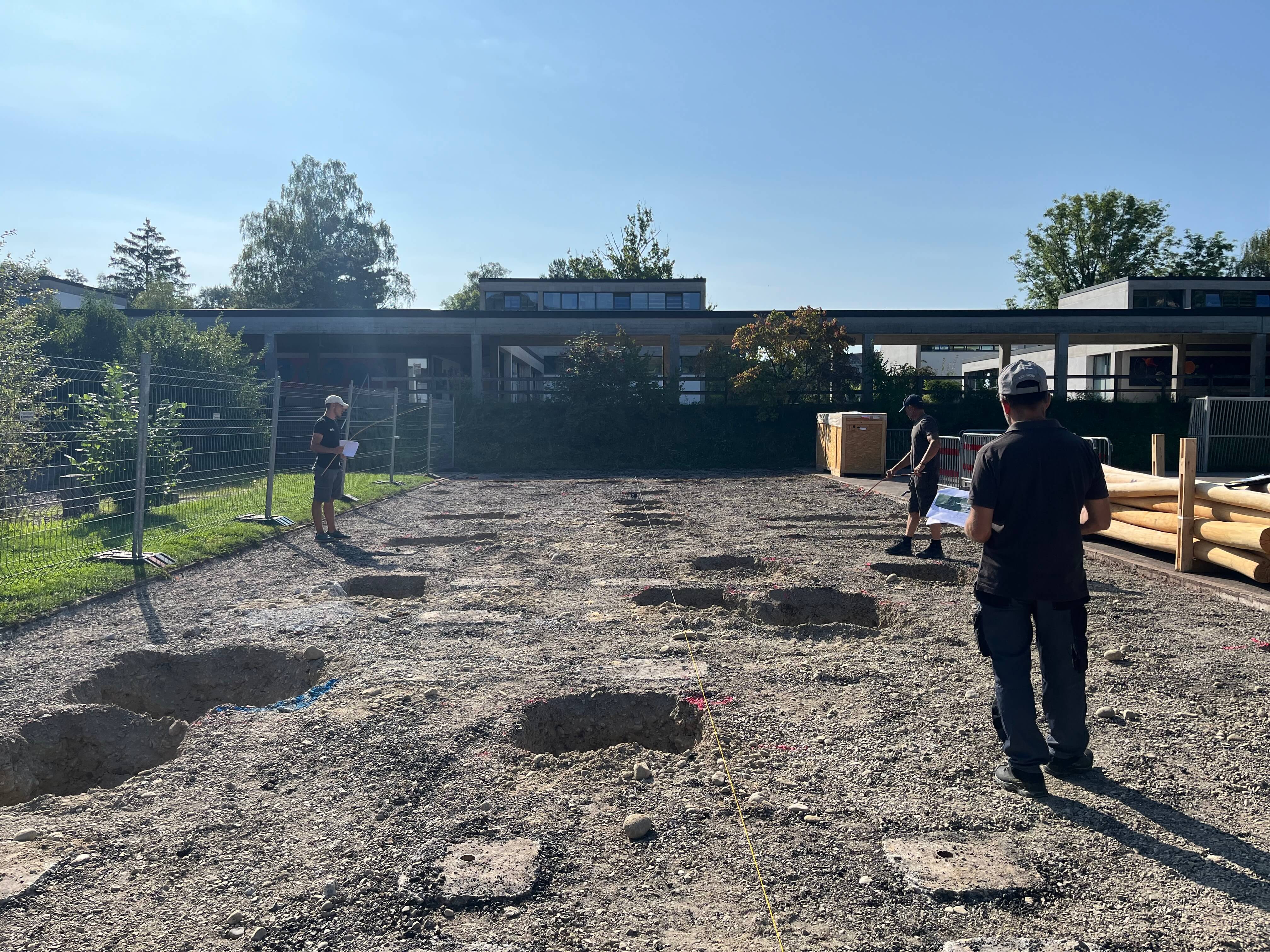 Mitarbeiter auf einer sonnigen Baustelle mit vorbereiteten Erdgruben