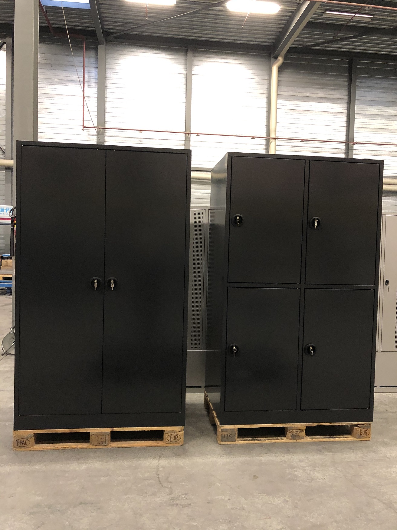 Deux grandes armoires en acier noir, placées sur des europalettes dans un entrepôt industriel.