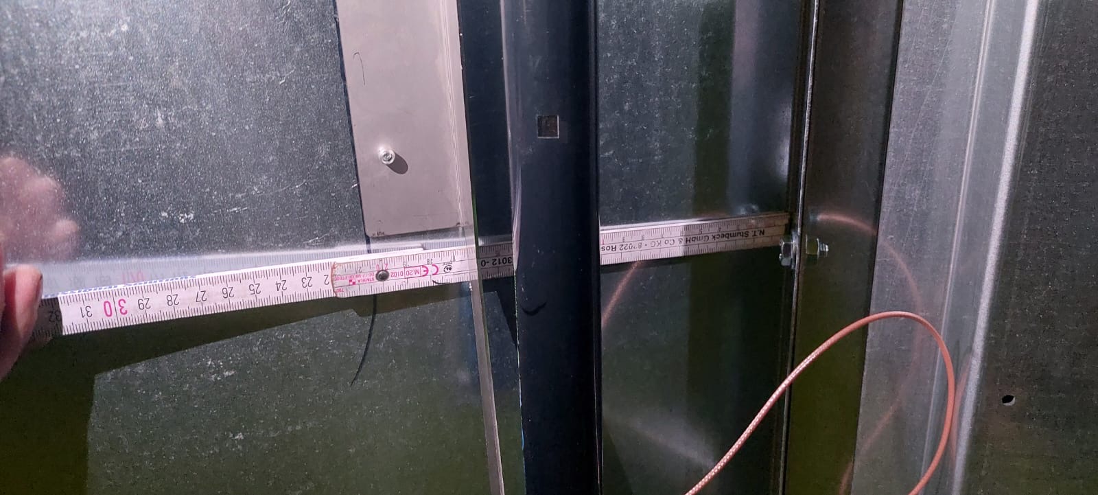 Ein Metalllineal wird für eine Messung vor einer metallenen Oberfläche verwendet, um genaue Abmessungen zu erhalten.