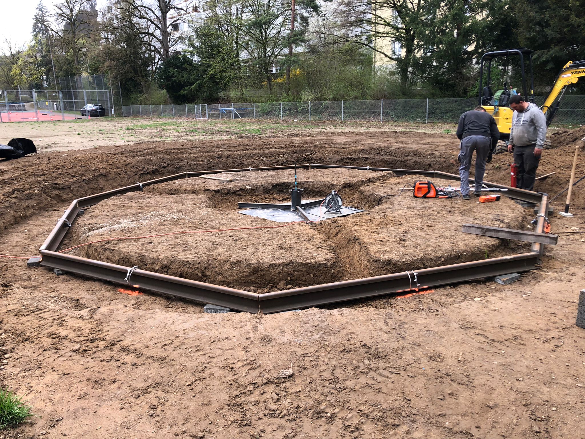 Zwei Arbeiter beim Bau einer runden Struktur aus Metallrahmen im Freien