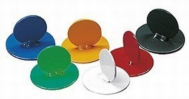 Six aimants ronds colorés de différentes couleurs comme le bleu, le jaune, le vert, le noir, le rouge et le blanc sur une surface blanche.